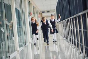 crianças da escola ativas de uniforme correndo juntas no corredor. concepção de educação foto