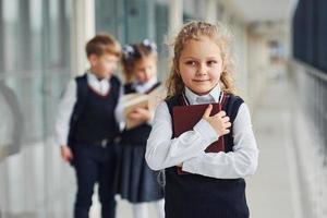 crianças da escola de uniforme junto com livros no corredor. concepção de educação foto