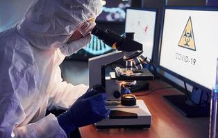 visão lateral do cientista em uniforme protetor branco que trabalha com coronavírus em laboratório foto