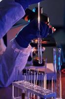 cientista em uniforme protetor branco trabalha com coronavírus e tubos de sangue em laboratório foto