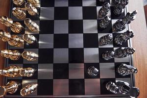 tabuleiro de xadrez com figuras de metal dentro de casa sobre a mesa durante o dia foto