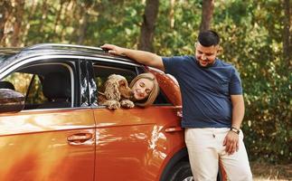 casal se diverte junto com cachorro no carro na floresta foto