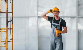 homem de uniforme cinza perto da construção faz uma pausa dentro de casa em um grande escritório moderno durante o dia foto