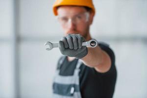 homem de uniforme cinza com chave na mão em pé dentro de casa no grande escritório moderno durante o dia foto