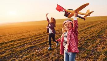 duas amigas se divertem juntas com pipa e avião de brinquedo no campo durante o dia ensolarado foto