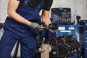 reparador profissional na garagem trabalha com motor de automóvel quebrado foto