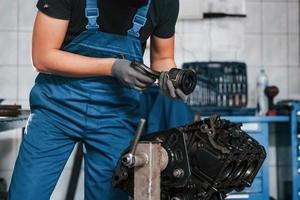 reparador profissional na garagem trabalha com motor de automóvel quebrado foto