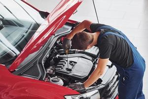 vista superior do trabalhador masculino de uniforme que conserta automóvel vermelho foto