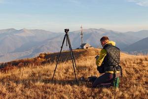 fotógrafos masculinos em pé e trabalhando na majestosa paisagem de árvores de outono e montanhas no horizonte foto