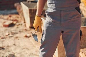 visão aproximada do trabalhador da construção civil em uniforme e equipamento de segurança em pé no prédio foto