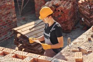 segurando o plano nas mãos. trabalhador da construção civil em equipamentos uniformes e de segurança tem trabalho na construção foto