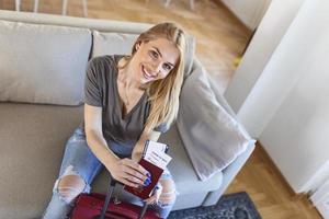 mulher feliz planejando uma viagem durante a pandemia de covid-19, preparando uma mala. mulher preparando a viagem de férias. segurando passaporte, passagem e teste negativo de coronavírus na mão foto