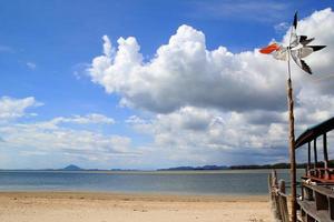 viajar para a ilha koh lanta, tailândia. o cata-vento no fundo do céu nublado, mar azul e praia de areia. foto