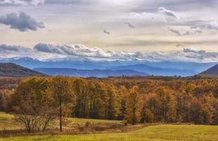 bela paisagem com árvores coloridas de outono com montanhas nevadas ao fundo. foto