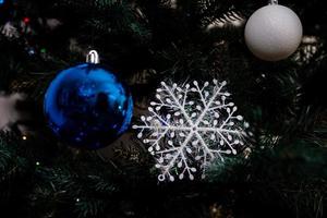 árvore de natal com bolas coloridas e caixas de presente sobre parede de tijolos brancos com bolas azuis e brancas foto