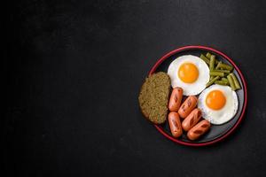 saboroso café da manhã inglês com ovos fritos, feijão, aspargos, salsichas com especiarias e ervas foto