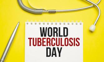 palavras do dia mundial da tuberculose no notebook e estetoscópio em fundo amarelo foto