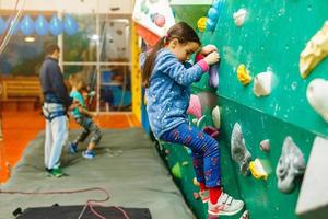 menina escalando uma parede de pedra interior foto