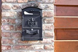 aço velho, caixa de correio de ferro na parede de tijolos de pedra, ao lado da cerca de madeira no prédio ou na porta da casa. objeto relacionado à casa, caixa de correio foto