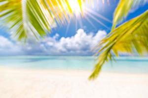 bela praia borrão, árvore de folha de palmeira verde, tempo ensolarado, raios de sol com vista para o mar azul e horizonte. paisagem de praia tropical para banner de turismo de férias de verão, desfocar o conceito de bokeh usar modelo de site foto