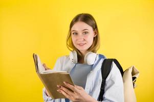 menina jovem estudante alegre na camisa azul com mochila segurando o livro. educação no conceito de faculdade universitária do ensino médio. banner copyspace foto