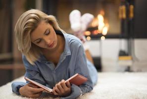 mulheres loiras perto de uma lareira lendo um livro. conceito de estilo de vida foto