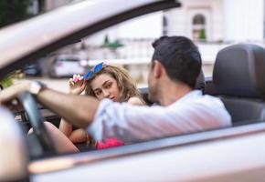 casal jovem feliz se divertindo em carro conversível em lindo dia de verão foto