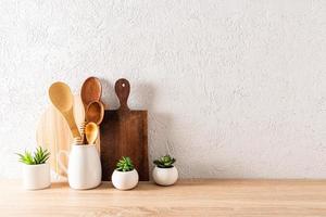 fundo de cozinha para o layout com tábuas de corte, colheres de pau no jarro e plantas em vasos. minimalismo. uma cópia . foto