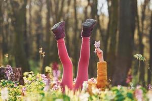 menina feliz em roupas casuais, deitado no chão na floresta de primavera durante o dia foto