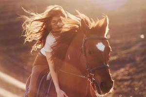 jovem de chapéu protetor com seu cavalo no campo agrícola durante o dia ensolarado foto