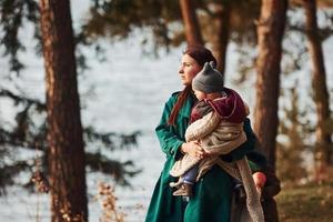 mãe com seu filho pequeno dá um passeio na floresta de primavera durante o dia foto