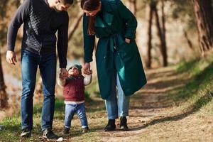 mãe e pai com seu filho pequeno passeiam na floresta de primavera durante o dia foto