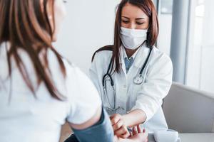 medição da pressão arterial. jovem tem uma visita com médica na clínica moderna foto