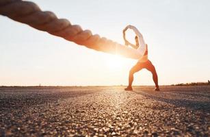 mulher em treinamento esportivo com nós na estrada ao entardecer foto