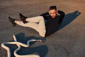 fazendo abdominais. homem em roupas esportivas tem dia de fitness na estrada ao entardecer foto