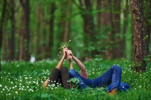 casal deitado na grama na floresta juntos durante o dia foto