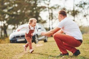 pai em roupas casuais caminha e se diverte com a filha ao ar livre perto da floresta foto