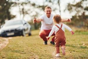 pai em roupas casuais caminha e se diverte com a filha ao ar livre perto da floresta foto