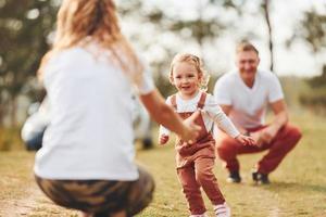 pai e mãe passando fim de semana ao ar livre perto da floresta com a filha foto