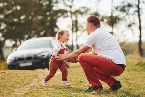 pai em roupas casuais caminha e se diverte com a filha ao ar livre perto da floresta foto