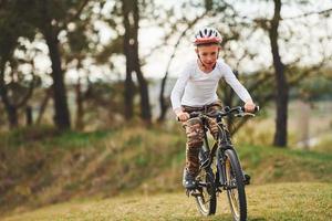menino andando de bicicleta ao ar livre na floresta durante o dia foto