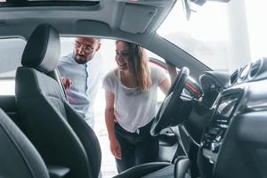 jovem positiva tem uma visita no salão de beleza e escolhe o carro. gerente ajudando ela foto