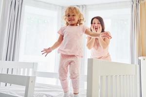 jovem mãe com sua filha em roupas casuais juntos dentro de casa em casa foto