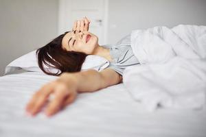 dormindo na cama. jovem descansando e passando o fim de semana em casa sozinha em casa foto