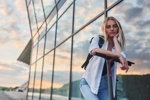 contra a construção de negócios modernos. linda loira em roupas casuais andando de escuna elétrica ao ar livre durante o dia ensolarado foto