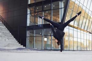 fazendo truques malucos. jovem morena em roupas esportivas tem dia de fitness ao ar livre na cidade foto