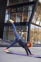 jovem ruiva europeia em roupas esportivas fazendo fitness ao ar livre foto