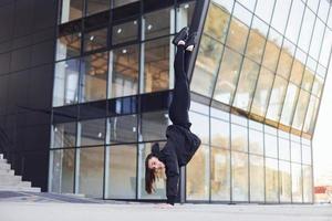 fazendo truques malucos. jovem morena em roupas esportivas tem dia de fitness ao ar livre na cidade foto