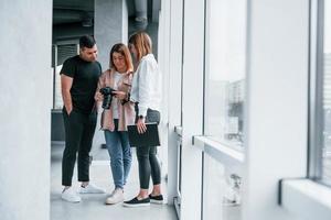 grupo de pessoas em pé dentro de casa juntos e olha as fotos na câmera