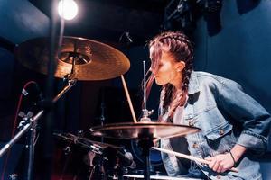 toca bateria. jovem bela artista feminina ensaiando em um estúdio de gravação foto